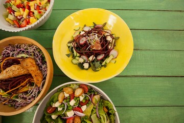Fresh food in bowls on green wooden table