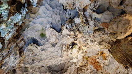Inside Thien Cung Cave, Ha Long bay, Vietnam, showcasing dramatic stalactites and rugged limestone formations illuminated by soft lighting.