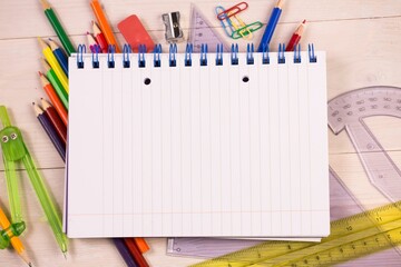 Flat design showing notebook on wooden desk surrounded by pencils, rulers, compass, copy space