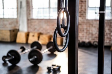 Flat design gymnastic rings are hanging in brick wall gym, with barbells, kettlebells, plyo boxes