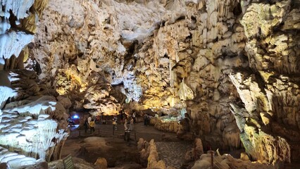 Inside Thien Cung Cave, Ha Long bay, Vietnam, showcasing dramatic stalactites and rugged limestone formations illuminated by soft lighting.