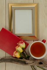Photo frame, lemon tea and flowers on wooden table