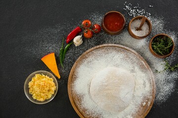 Dough with flour by ingredients in black table