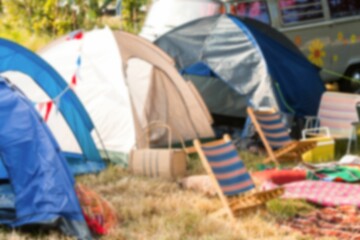 Tents by van and chairs on grassy field