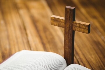 Cross kept by bible on wooden floor