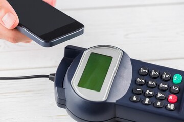 showing vector terminal, green screen and keypad on white table, hand tapping smartphone above slot