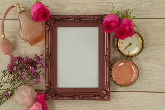 Photo frame, perfume and flowers on wooden table