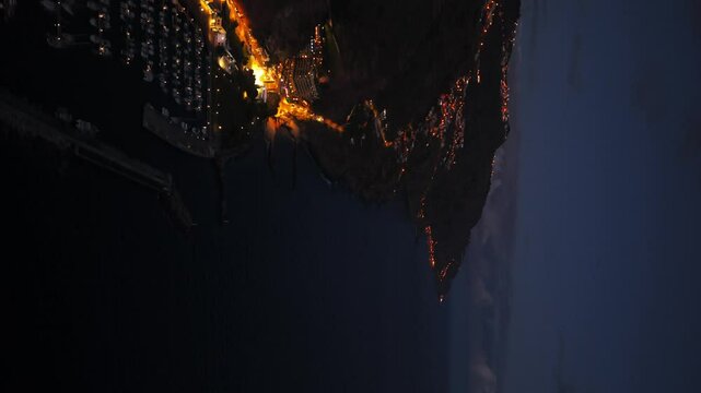 Calheta's lights creating a magical atmosphere at dusk, overlooking the vast Atlantic Ocean in Madeira, Portugal. Aerial, Vertical Video