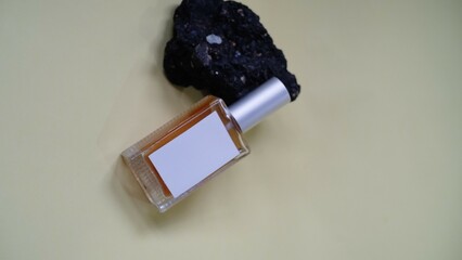 A luxury glass perfume bottle with cap containing  liquid lies on gray background, sprig of flowers...