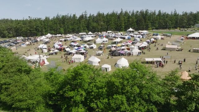Drone shot over a line of trees to reveal a Renaissance Fair on Whidbey Island, Washington.