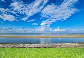 Tropical Beach View with Blue Sky, Clouds, and Green Grass Foreground