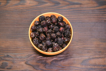 An overhead shot of dried rose hips, rich in vitamin C, presented in a vibrant orange bowl. The...