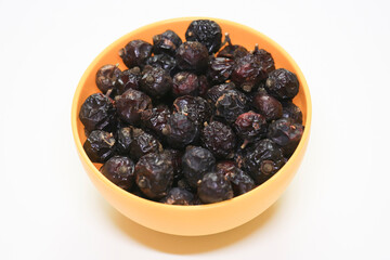 Bowl filled with dark, dried rose hips, a natural source of vitamin C, prominently displayed on a...