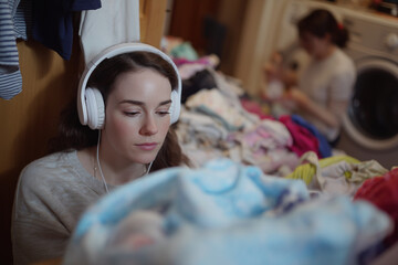 A woman wearing headphones is looking at a pile of clothes