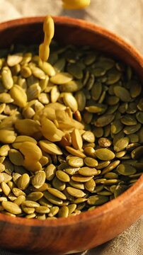 wooden bowl filled with pumpkin seeds on wooden table surrounded by pumpkins rustic autumn harvest setting
