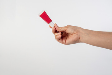 Red lipstick, small tube, and empty space and hand on white background.