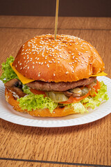 A delicious burger topped with cheese, lettuce, and pickles sits on a plate, ready to enjoy