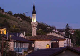 Mosque minaret in the evening on the background of a hill in summer.
