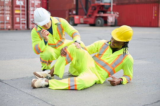 Industrial worker injured on site, his colleague providing immediate support, symbolizing workplace safety and accident response