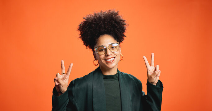 Smile, portrait and woman with peace sign, glasses and social media influencer for fashion. Happy African model, studio and v hand gesture for victory symbol or emoji on orange background with space - Powered by Adobe