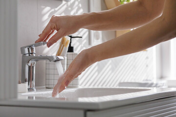 Washing hands under running water in sunny modern bathroom with minimalist decor and hygiene focus