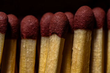 A macro photograph capturing the textured red tips of matchsticks lined up closely.