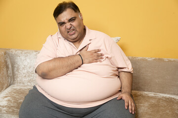 Overweight fat indian man suffer from chest pain at home. Obese guy dyspnea problem. healthcare and...