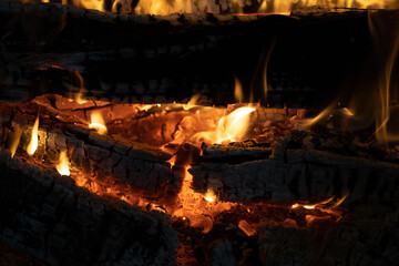 Detailed view of burning wood with glowing embers and lively flames creating a warm atmosphere.