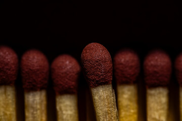Close-up of matchstick heads with red tips in a dark, atmospheric background.