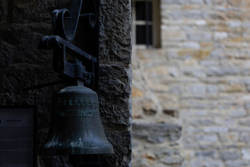 A weathered bronze bell mounted on a textured stone wall, evoking historical charm.