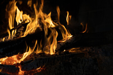 Close-up of vibrant flames consuming logs in a dark fireplace, creating a cozy ambiance.