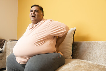 Overweight indian man suffer from backache. Plus size guy have pain in spine due to excess belly fat. Healthcare and Obesity problem