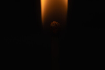 Intimate view of a matchstick igniting in the dark, capturing the delicate flame.