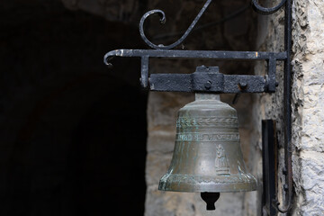 Close-up of a vintage bronze bell affixed to a textured stone wall, emanating historic charm.