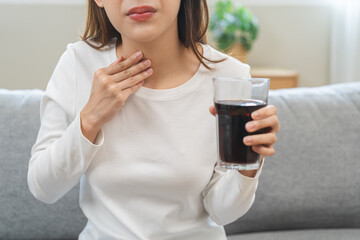 Acid reflux disease, suffer asian young woman, girl hand holding a glass of cola, have symptom...