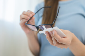 Cleaning glasses concept, hand of asian young woman hand holding frame of glass, using tissue paper wet wipe lens, rub to clean eyewear for sanitary with wipe remove dust and disinfect at spectacle.