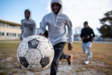 A group of students playing with a soccer ball in a schoolyard, soft afternoon light,