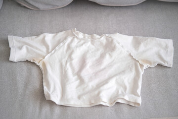 A yellow spot on a white T-shirt. Top view.