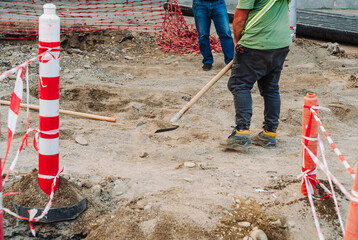 City infrastructure repair scene with open roads, red polypropylene pipes, construction workers, and excavation equipment. Urban utilities and roadwork maintenance in progress