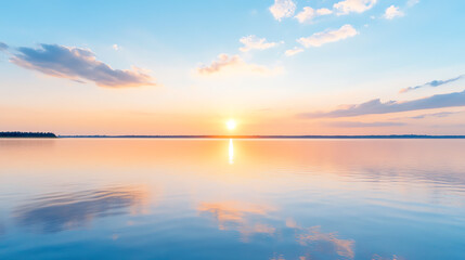 Fototapeta premium A serene sunset over a calm lake, reflecting vivid colors of orange, pink, and blue in the water, creating a peaceful atmosphere.
