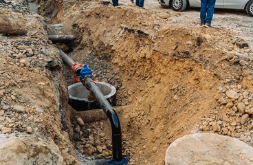 City infrastructure repair scene with open roads, red polypropylene pipes, construction workers, and excavation equipment. Urban utilities and roadwork maintenance in progress