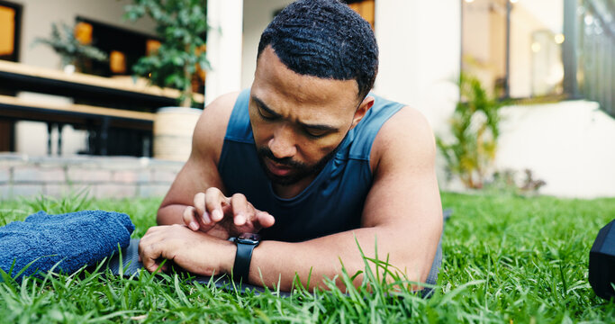 Exercise, break and man with smart watch, outdoor or check heart rate on app, exhausted and fitness. House, lawn and person with timer for workout progress, tired and tech with stats for routine