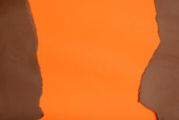 A bold orange backdrop framed by irregularly torn edges of deep brown paper