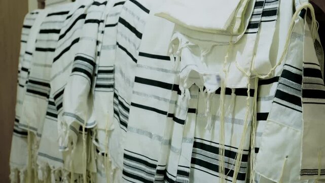 The tallit Jewish prayer shawls hanging neatly, in a synagogue or place of worship. The tallitot with knotted fringes tzitzit.