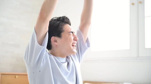 ベッドの上で寝起きで伸びやストレッチをする男性の動画の全身　よく寝た～と腕を伸ばすの動画