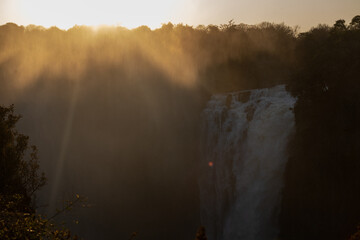 Backlit image of the Victora falls in Zimbabwe, illustrating a light spray of mist coming off the...