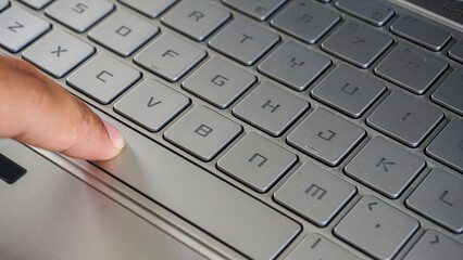 Full frame and close up view of finger pressing space button of a laptop keyboard isolated on black...