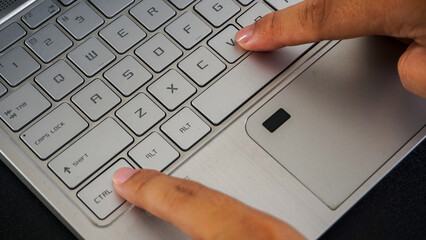 Close up view of finger pressing control and V letter button or ctrl + V on laptop keyboard,...