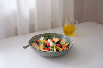 A vibrant salad of fresh ingredients - peaches,spinach, strawberry, cheese drizzled with olive oil, showcasing the essence of healthy eating.