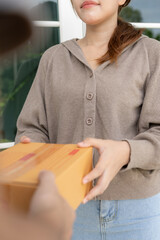 Happy smiling woman receives boxes parcel from courier in front house. Delivery man send deliver...